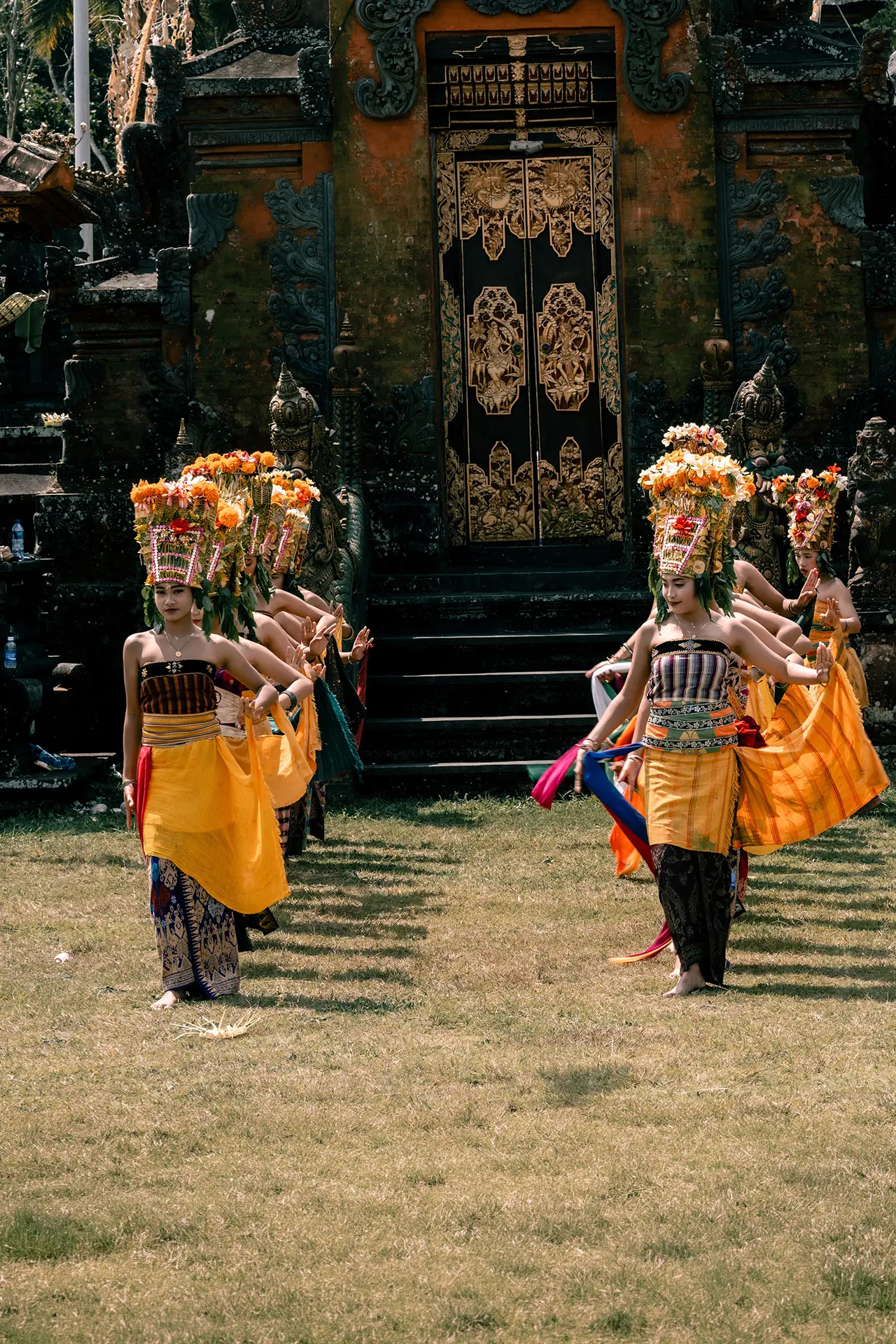 Balinese dancers in traditional dress performing before a temple.